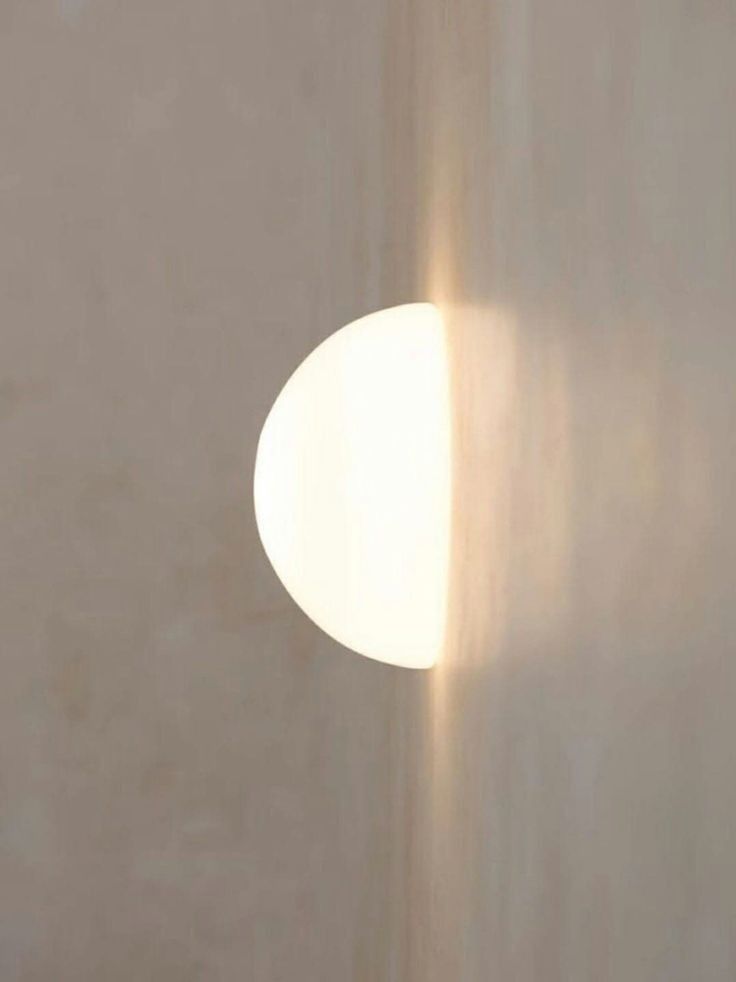 White spherical object casting a shadow on a textured beige wall
