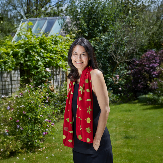 Woman wearing a red scarf with floral patterns in a garden setting