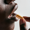 Close-up of a beautiful woman about to take an orange color capsule pill of Neutrient Curcumi